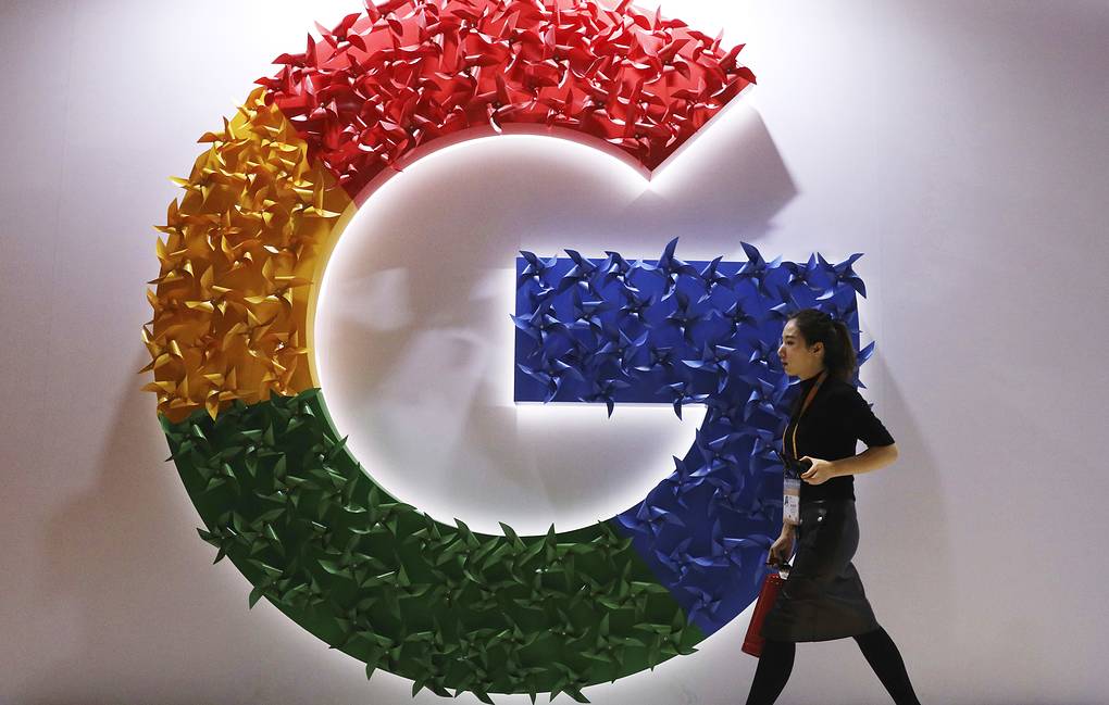 FILE - A woman walks past the logo for Google at the China International Import Expo in Shanghai, Nov. 5, 2018. Online companies would have to ramp up efforts to keep harmful content off their platforms and take other steps to protect users under rules that European Union lawmakers are set to vote on Thursday Jan. 20, 2022. (AP Photo/Ng Han Guan, File)