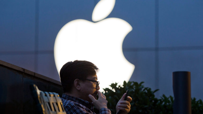 Asian man standing infront of Apple Apple Logo